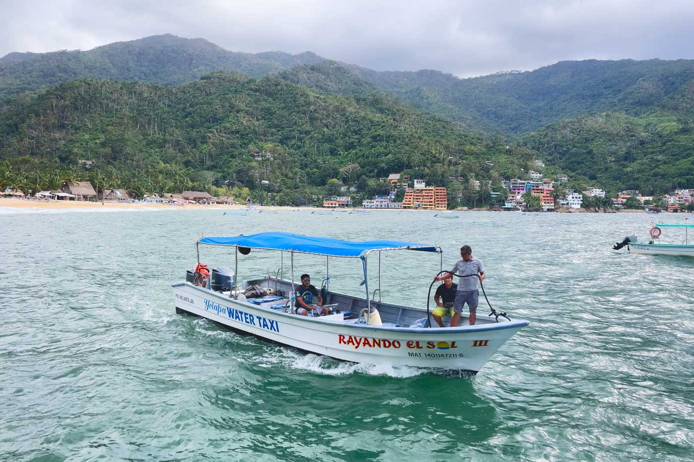 Water taxi navigating the waters surrounded by Yelapa's lush mountains.