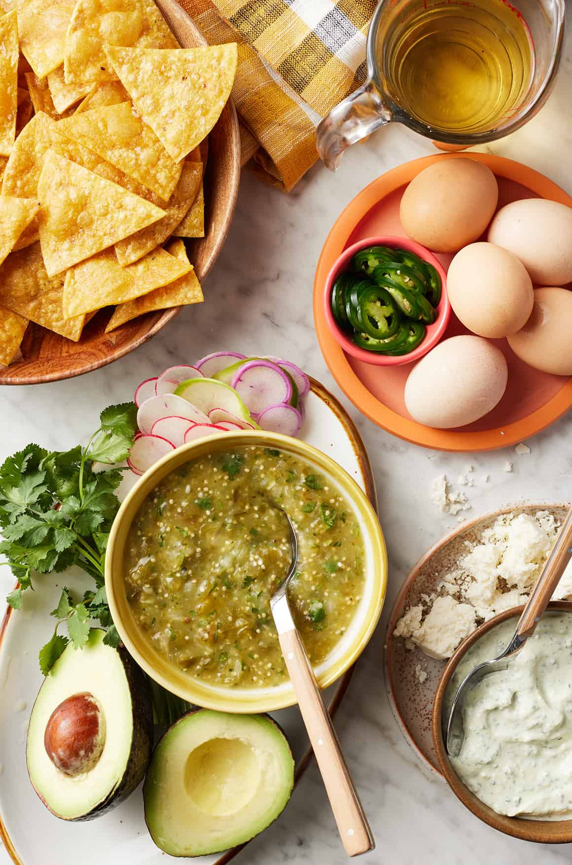 Ingredients for making chilaquiles recipe laid out on a wooden surface.