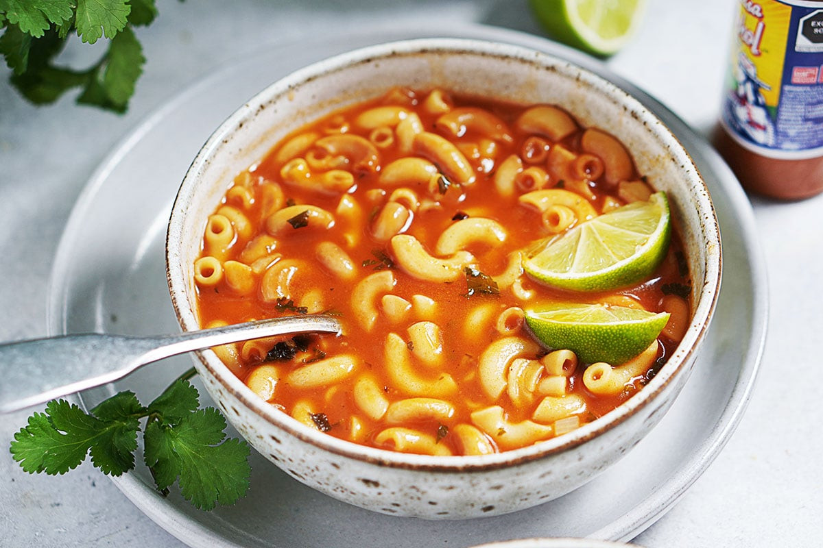 Bowl of mexican sopa with lime slices, ready to serve.