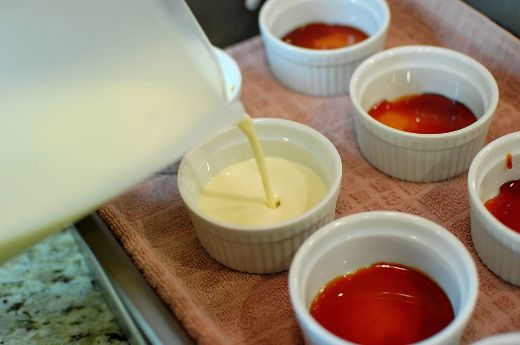 Ramekins filled with custard in a water bath.