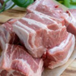 Pork butt being cut into large chunks