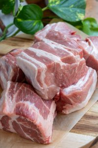 Pork butt being cut into large chunks