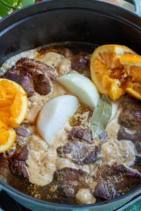 Adding onion, garlic, black pepper, cumin, Mexican oregano, cloves, and bay leaf