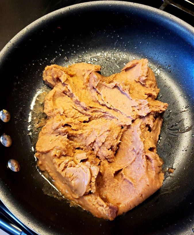 Frying refried beans with onion and garlic