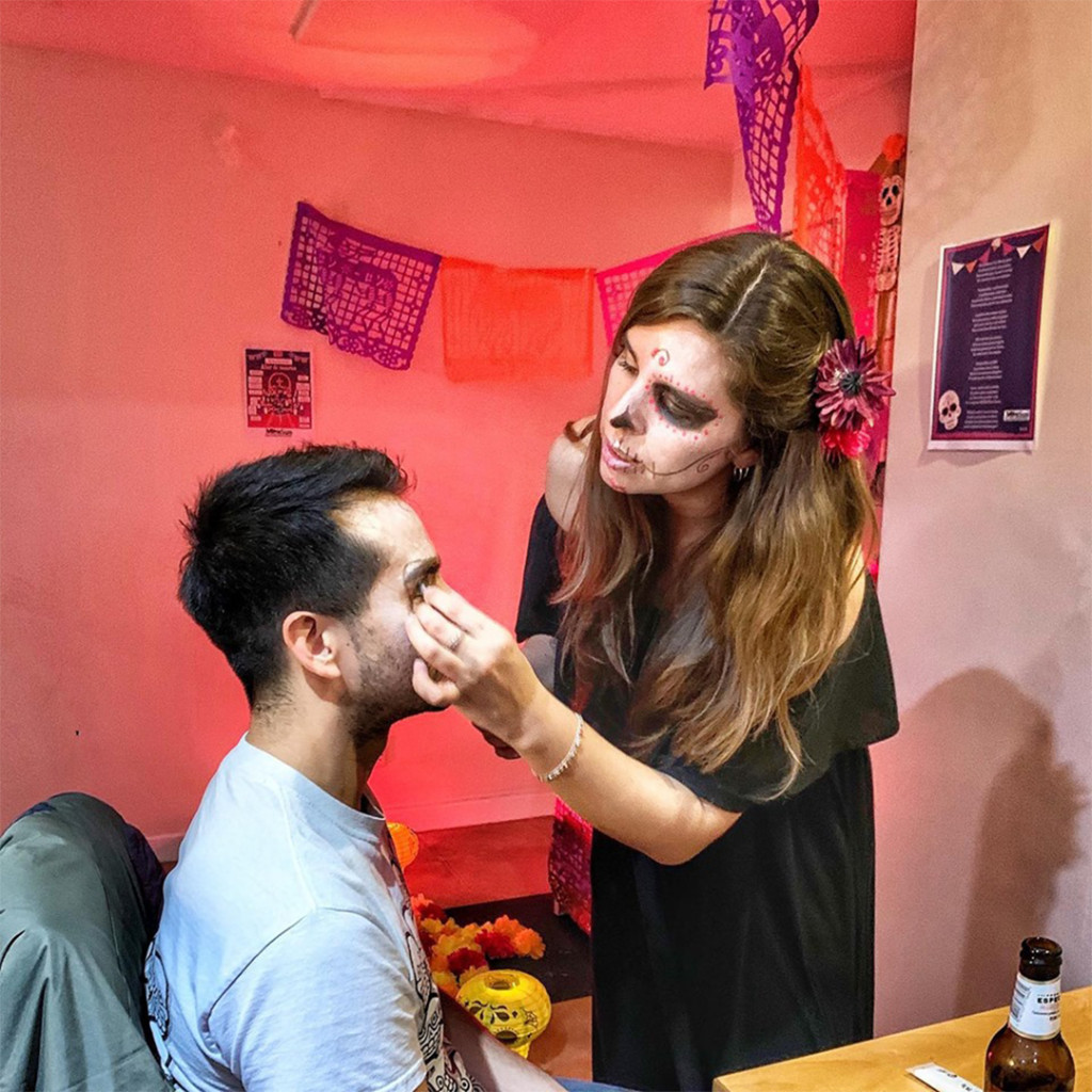 Sussex University scholars organizing a Day of the Dead event, inviting people to paint their faces as 'catrinas' and join in the celebration, fostering intercultural understanding and community engagement.