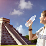 Young woman enjoying a cold drink at a bar in Cancun, featuring safe ice made from purified water.