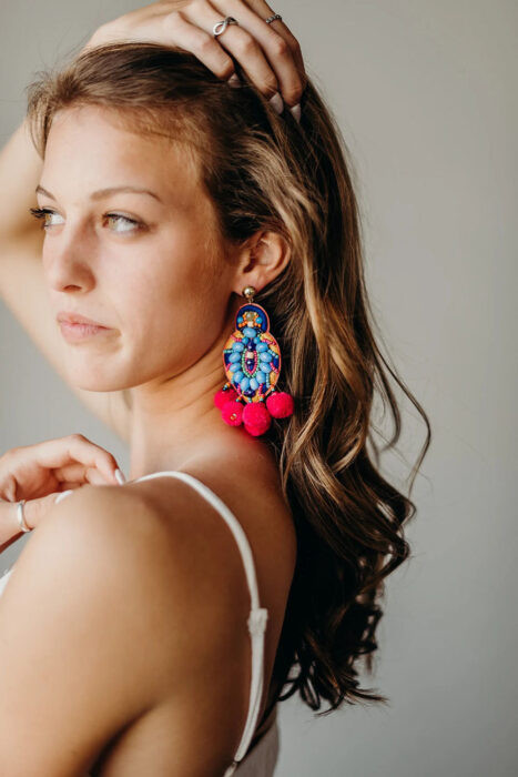 A woman with bold and colorful makeup, complemented by a traditional updo hairstyle adorned with flowers, perfect for a Mexican-themed party