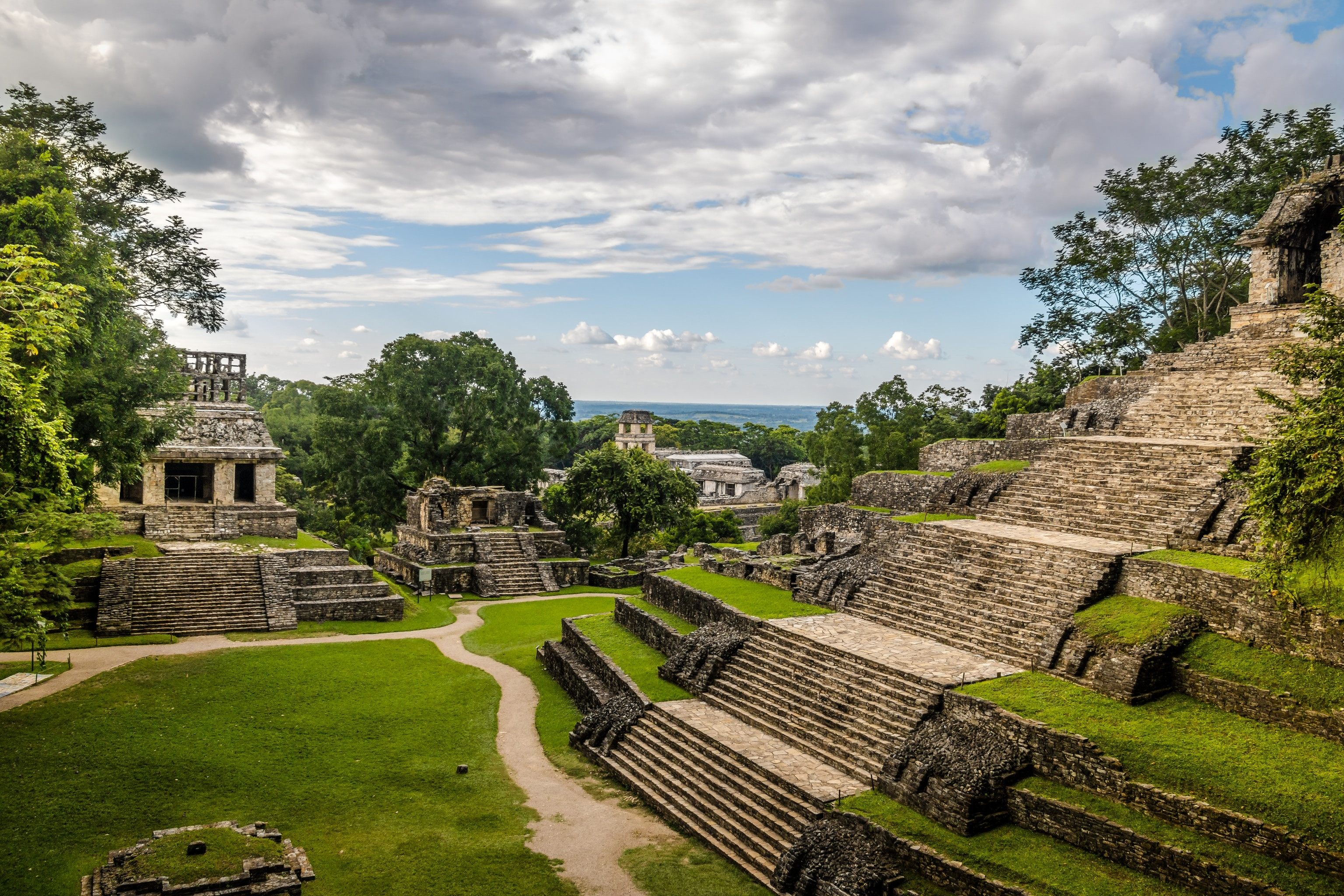 An ancient maya ruin in Palenque, southern Mexico. The grass is vibrant green and the sky is bright blue.