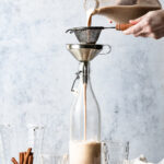 Showing how to make horchata, pouring blended mixture through a fine mesh sieve into a pitcher.