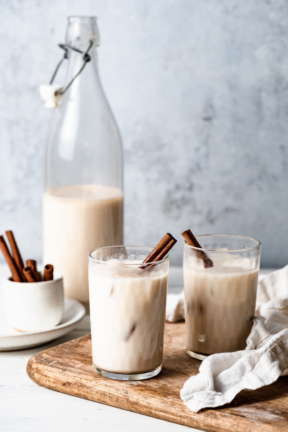 Two glass cups full of horchata with a pitcher half full of horchata in the background.