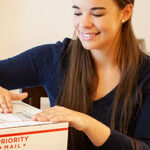 Young woman labeling a USPS Priority Mail International package.
