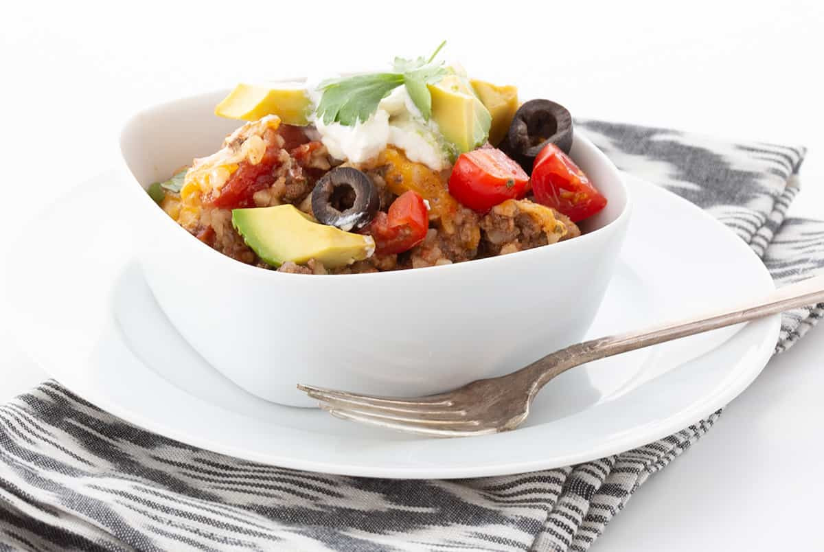 Close-up shot of Mexican cauliflower rice in a bowl, garnished with cilantro and a lime wedge, showcasing its vibrant colors and fresh ingredients.