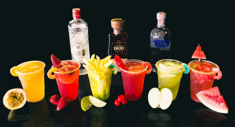 Micheladas in salt-rimmed glasses with lime wedges and chili powder, garnished with shrimp and olives, showcasing the diverse and flavorful variations of this beer cocktail.