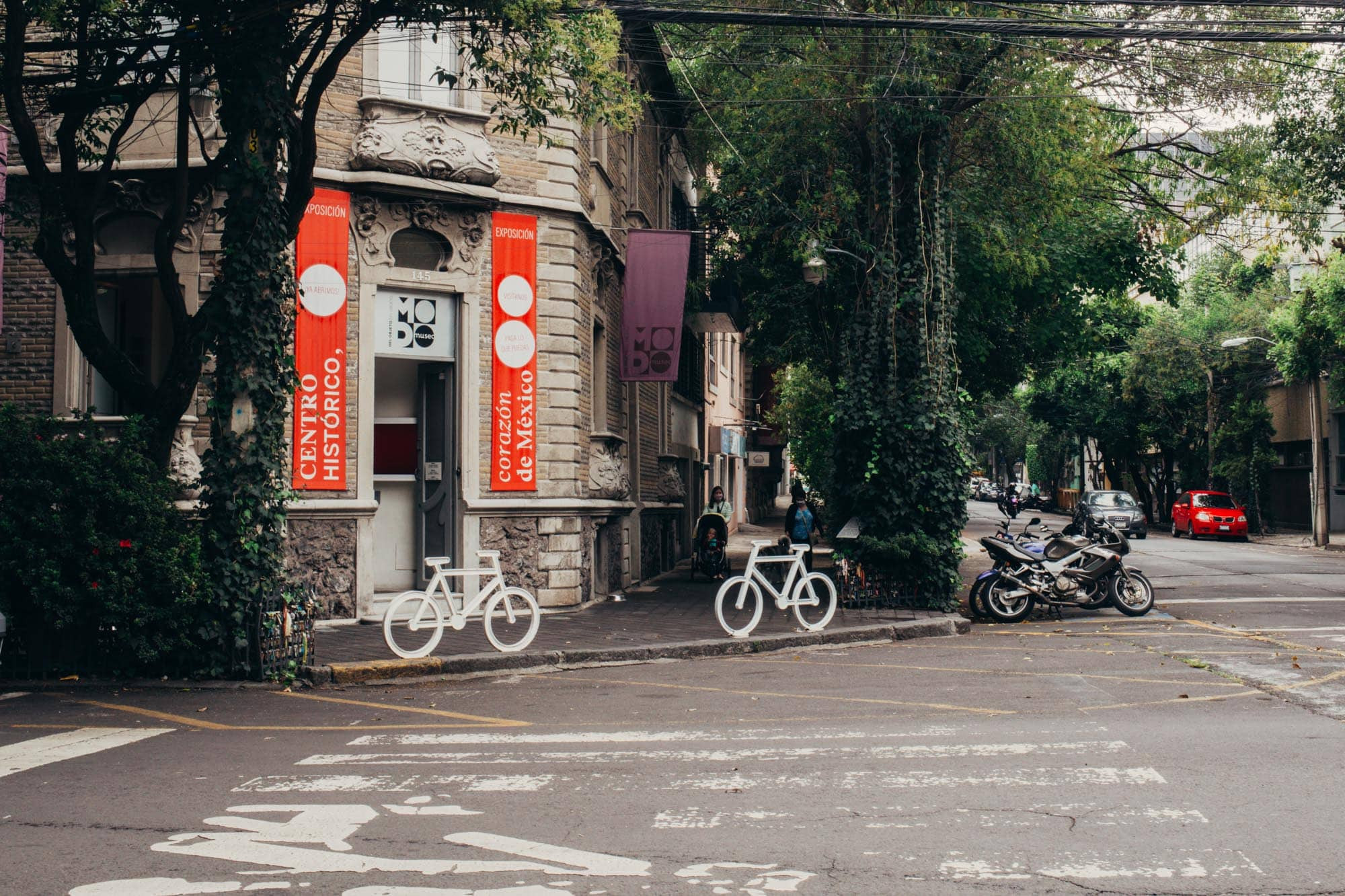 Cyclists and a motorbike parked on the tranquil street, encapsulating the lively spirit of Roma Norte, Mexico City.