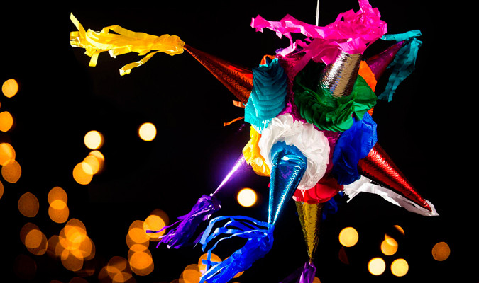 Breaking a traditional star-shaped piñata at a Posada celebration, Mexico