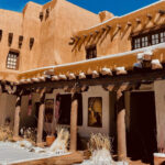Traditional adobe style building with a courtyard filled with snow in Santa Fe, New Mexico.