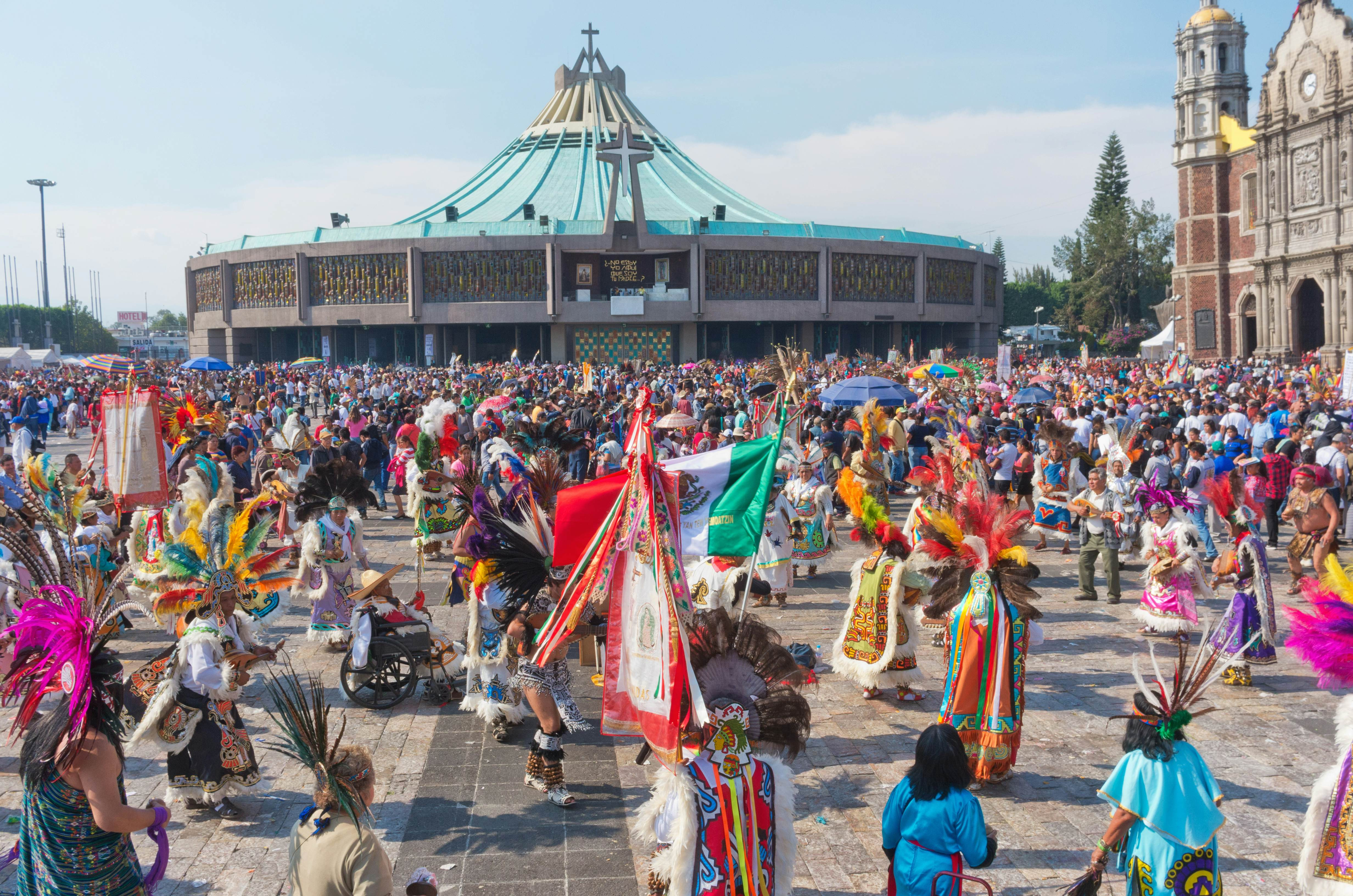 People dressed in traditional clothing parading in front of a cathedral in Mexico City