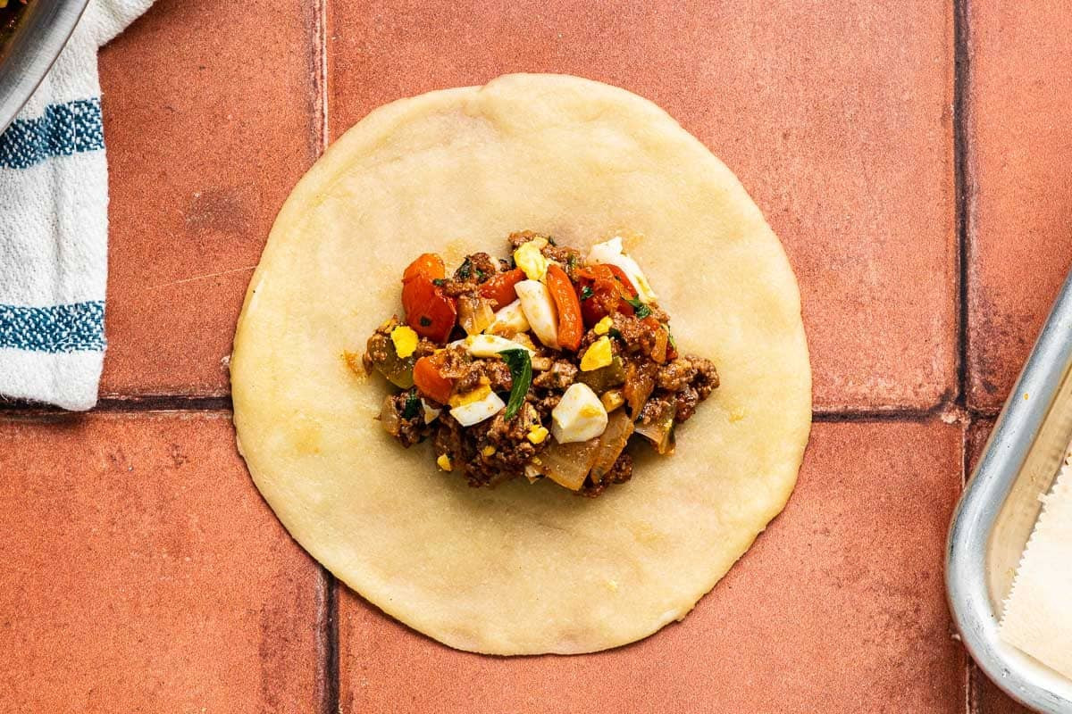 Spanish Beef Empanadillas filling placed in a circle of uncooked dough.