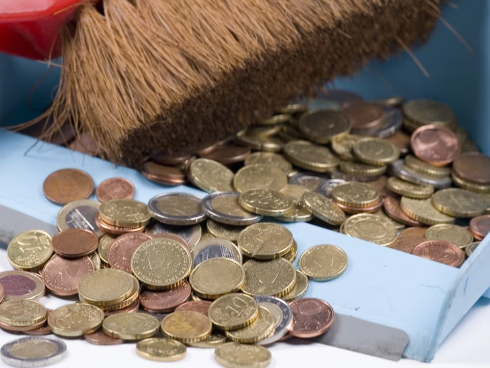 A person sweeping coins into a house, symbolizing a wish for prosperity in the New Year