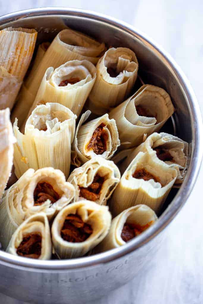 Pork tamales stacked in a pot, ready for steaming.