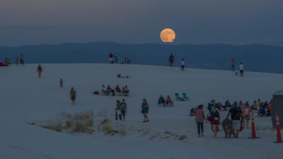 A family enjoying sledding down the white gypsum dunes at White Sands National Park, highlighting the recreational activities available.