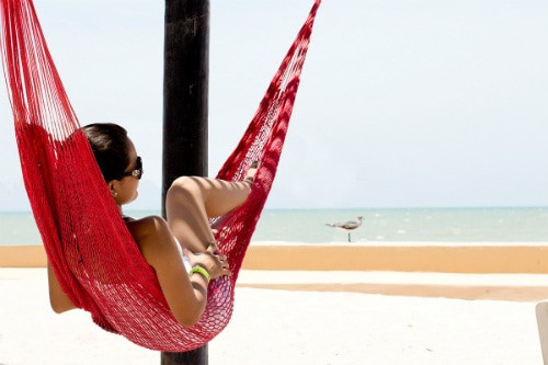 Woman relaxing on a red hammock overlooking the beach in Progreso
