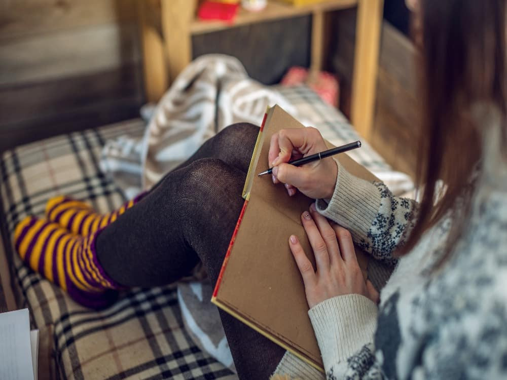 A person writing wishes on a piece of paper, setting intentions for the New Year