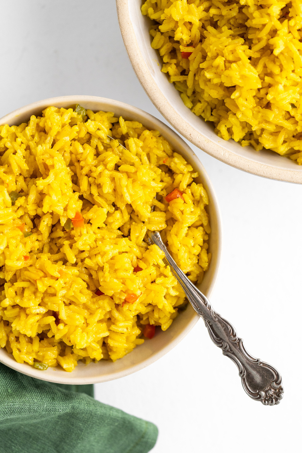 Two bowls of bright yellow Mexican rice on a table.