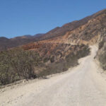 The dirt road to Puerto Santo Tomas winds through farmlands and steep mountainsides, requiring caution and a suitable vehicle.