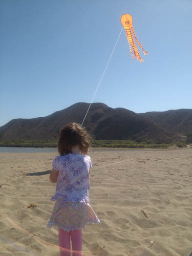 Maya flying her kite at La Bocana beach, enjoying a peaceful morning on the coast near Puerto Santo Tomas.