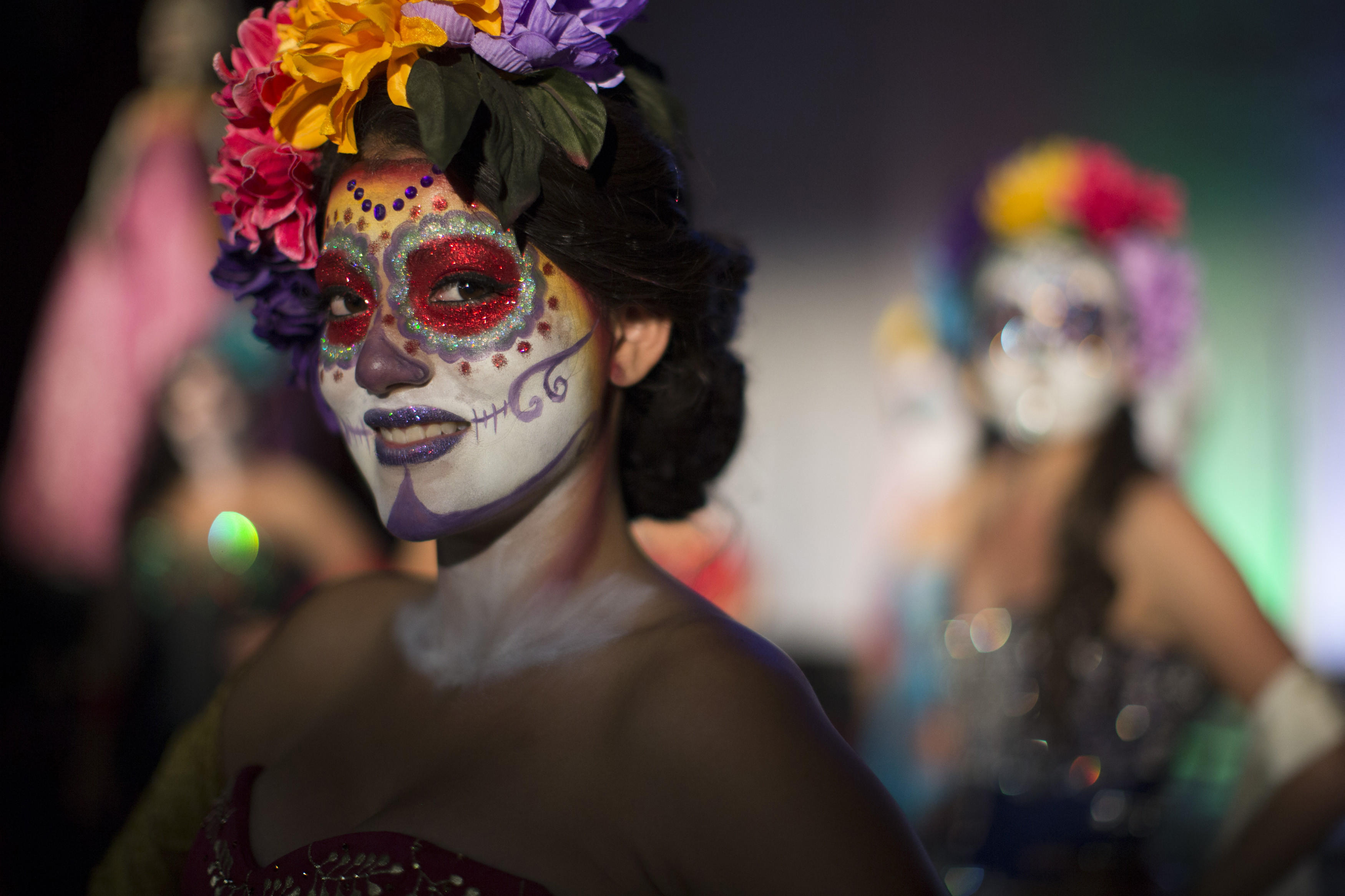 A vibrant Day of the Dead parade, featuring colorful costumes and sugar skull makeup, showcasing the holiday's evolution and cultural fusion.