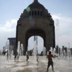 People frolic at the water fountain .