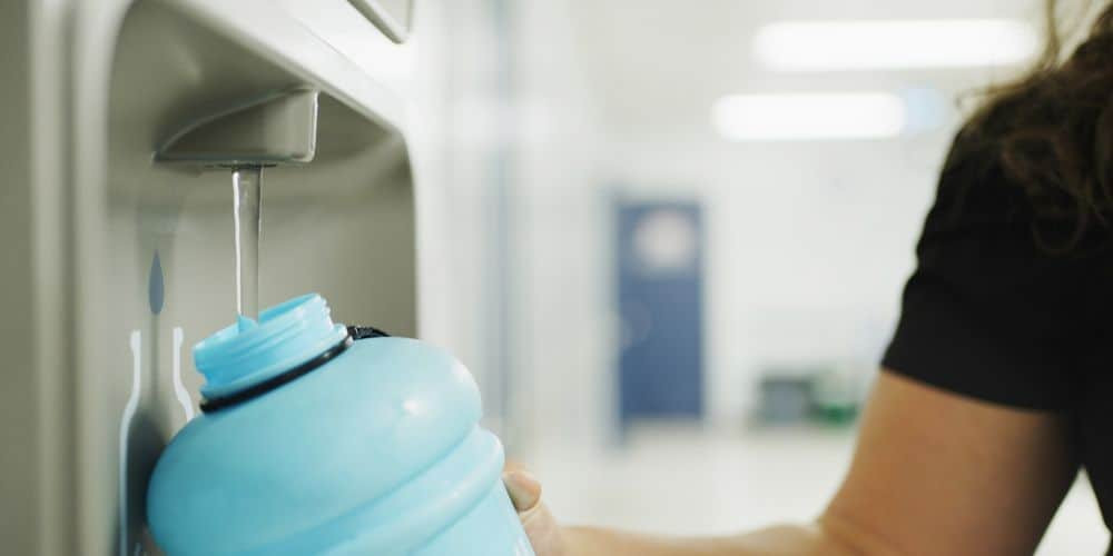 Refilling a water bottle at a water dispenser for sustainable hydration.