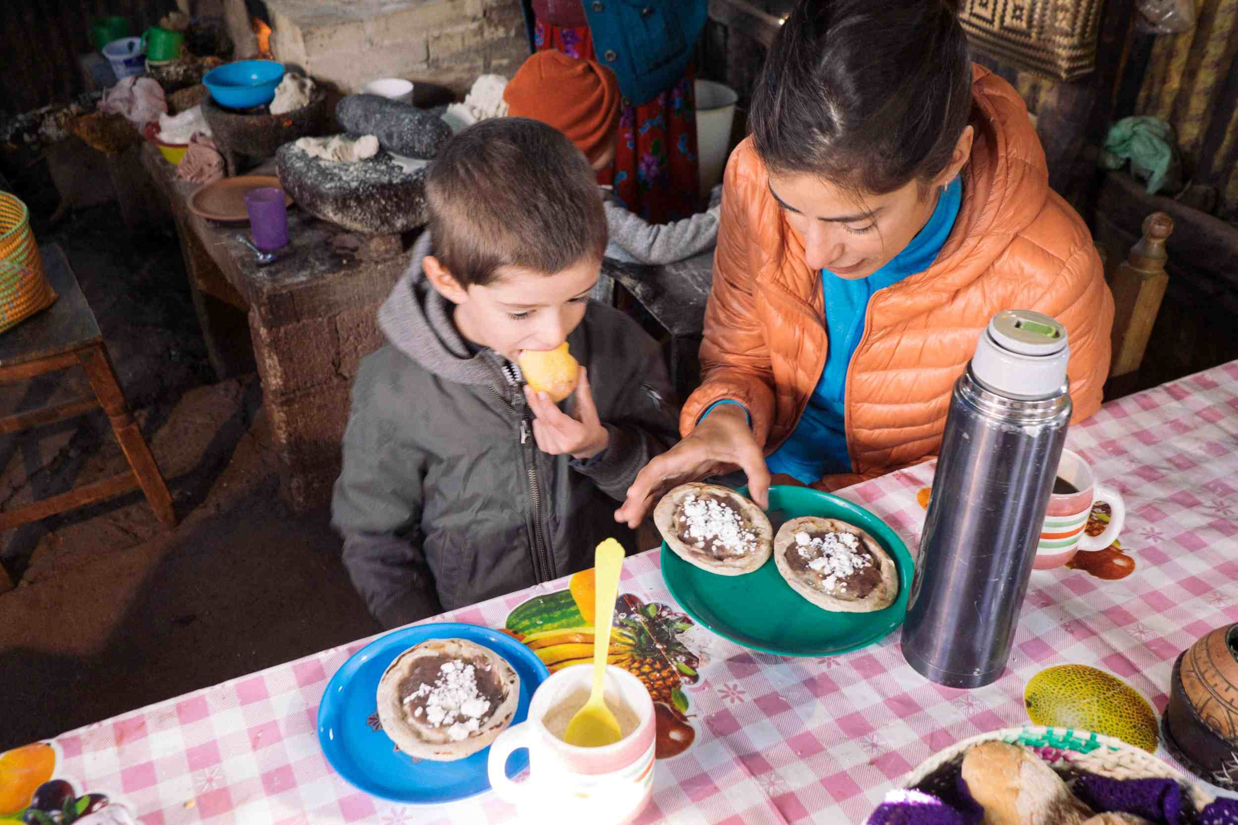 A traveler with her son tasting local food, capturing a moment of authentic cultural experience in Mexico.