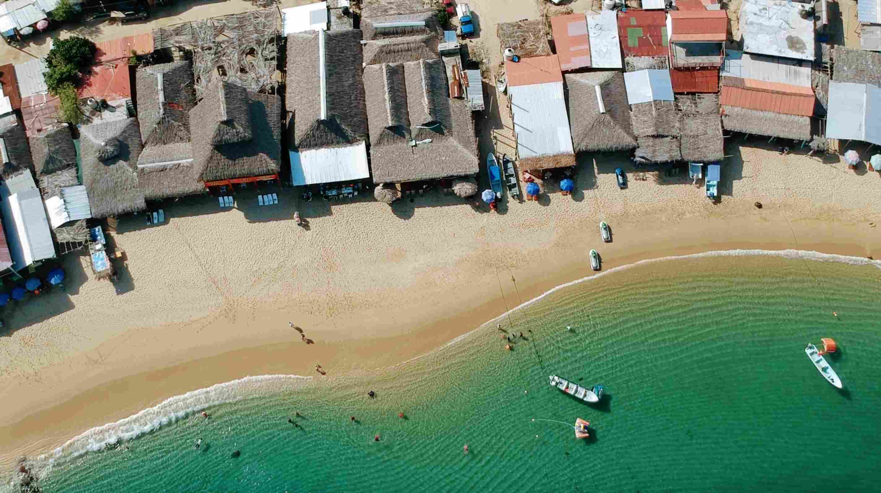 Stalls on the beach near the sea with boats sailing in Puerto Vallarta, offering a picturesque view of coastal life.