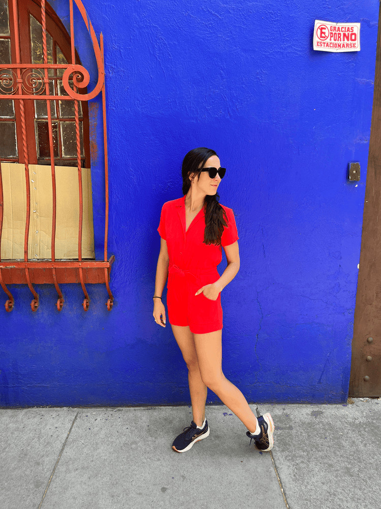 woman in red outfit in front of blue wall in roma condesa for where to stay in mexico city