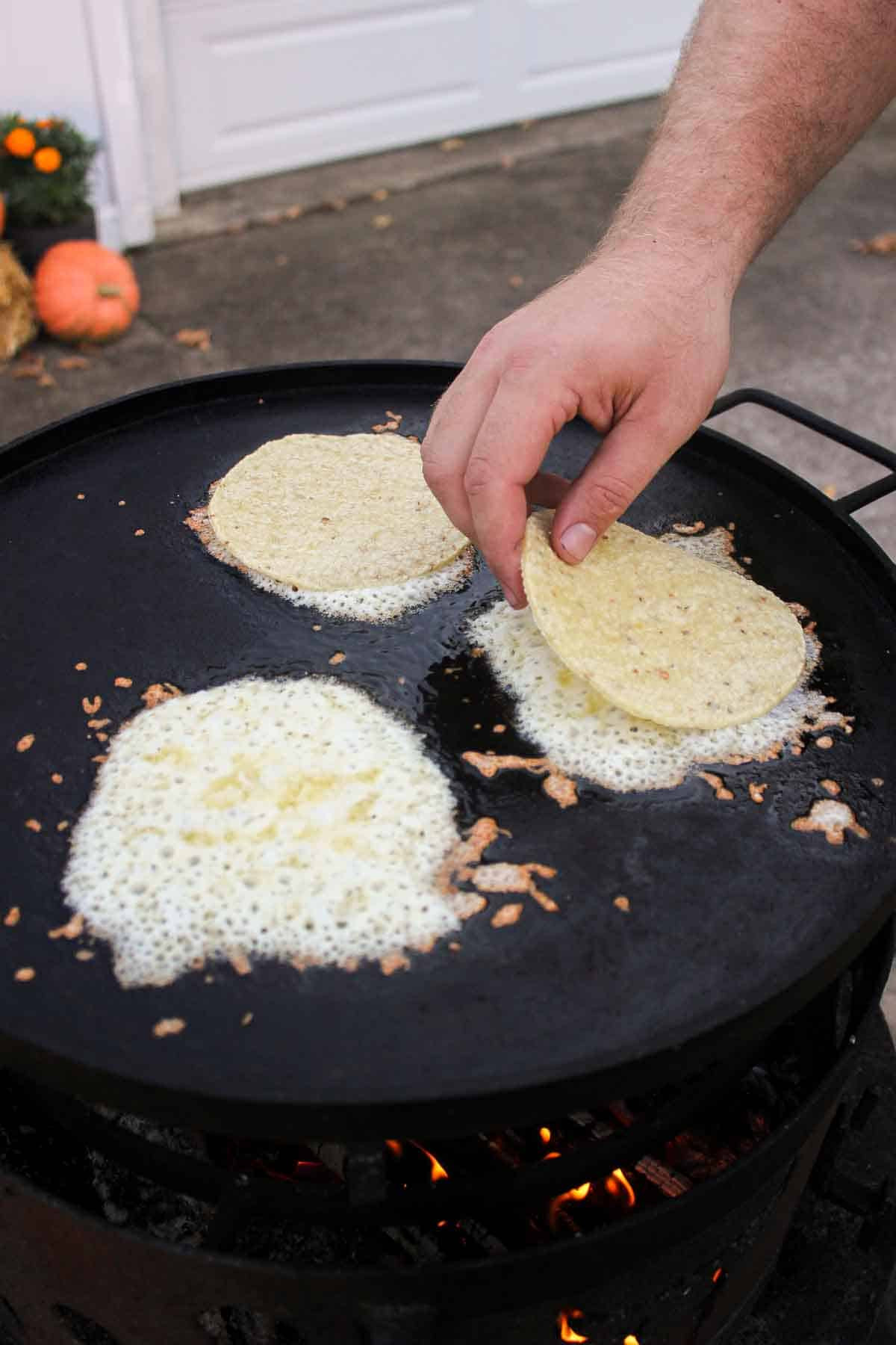 Placing the tortillas on top of the melted cheese. 