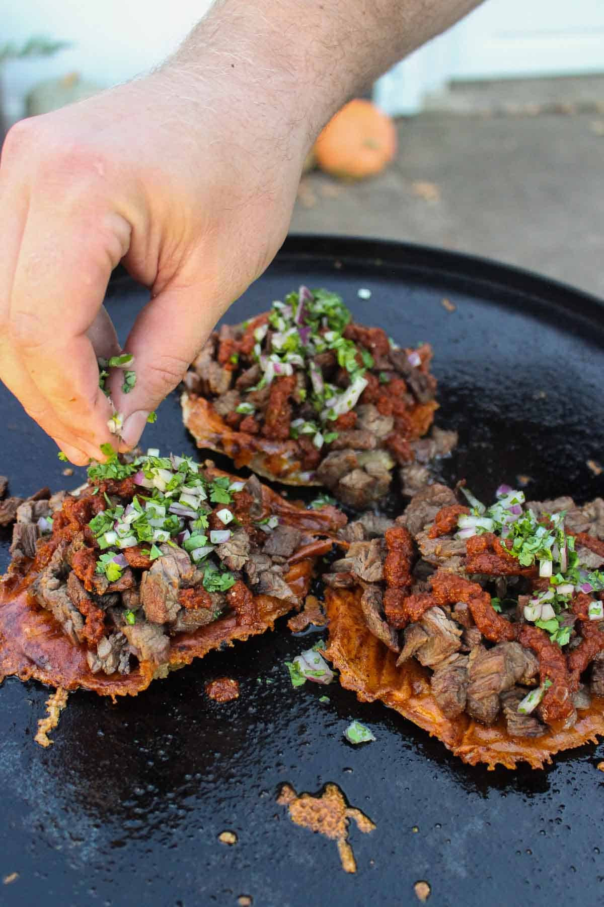 Adding cilantro and onions to the Grilled Steak Vampiro Tacos.