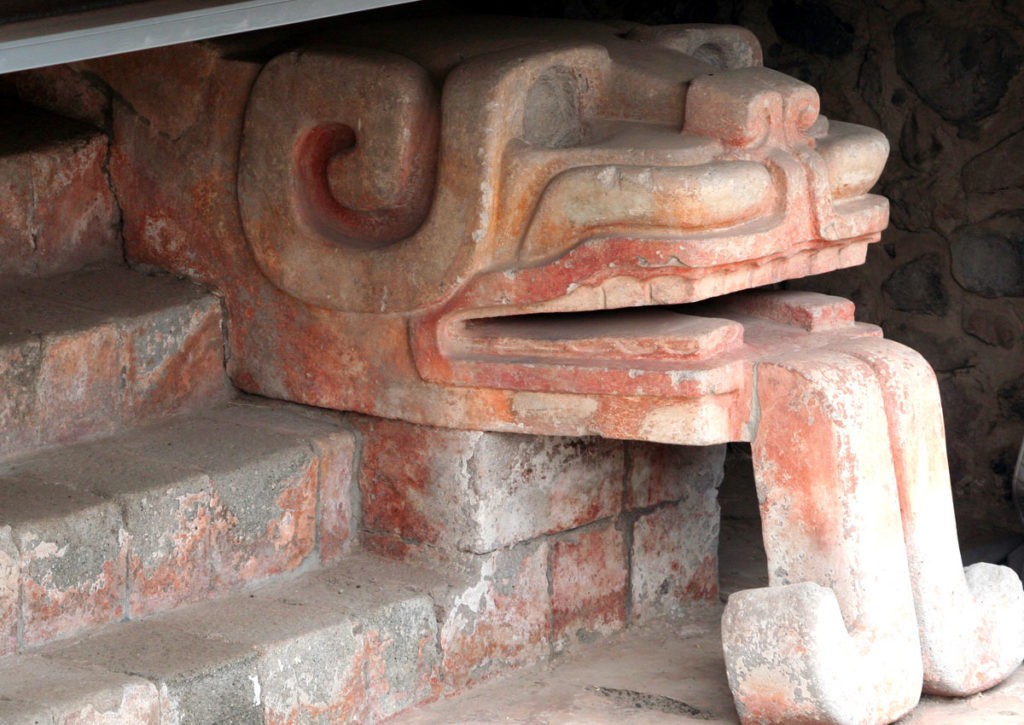 Figure with a jaguar's head and a snake's tongue at the base of a partially buried stairway in Teotihuacan, showcasing the artistic and symbolic richness of ancient Mexican culture
