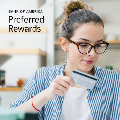 A woman holding Bank of America credit card, suggesting travel
