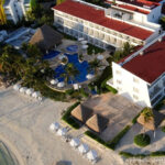 Aerial view of Cancun Bay Hotel highlighting its prime location near Isla Mujeres Bay, showcasing the resort's beautiful beachfront and pool areas.