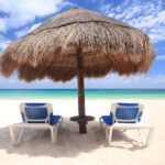 Beach chairs under thatched umbrella overlooking a tropical beach, Cozumel