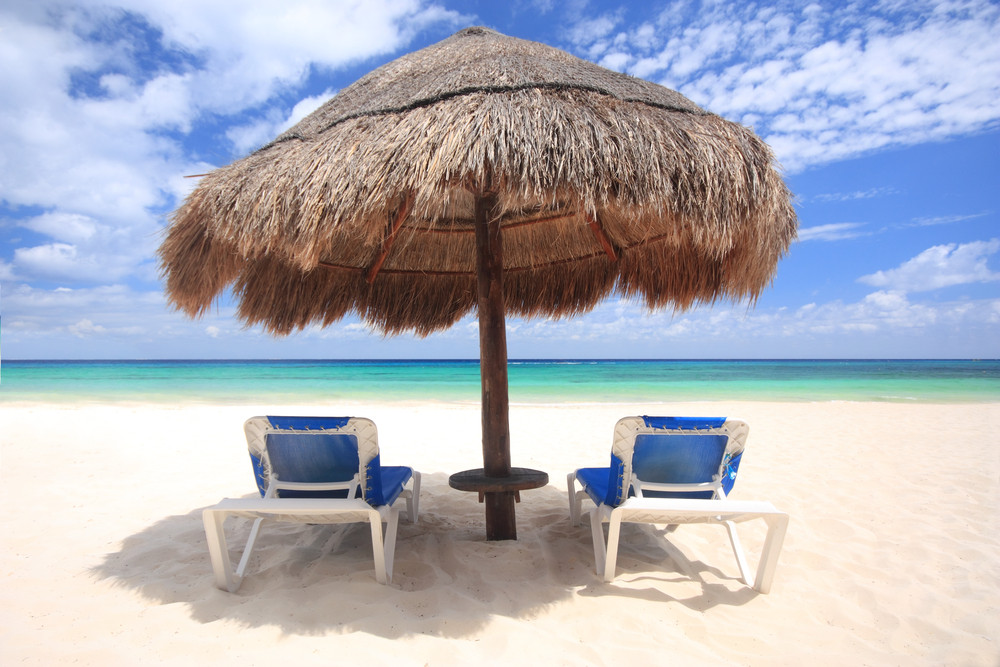 Beach chairs under thatched umbrella overlooking a tropical beach, Cozumel