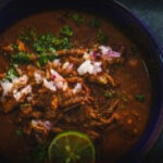 Bowl of Birria Stew garnished with cilantro and onions
