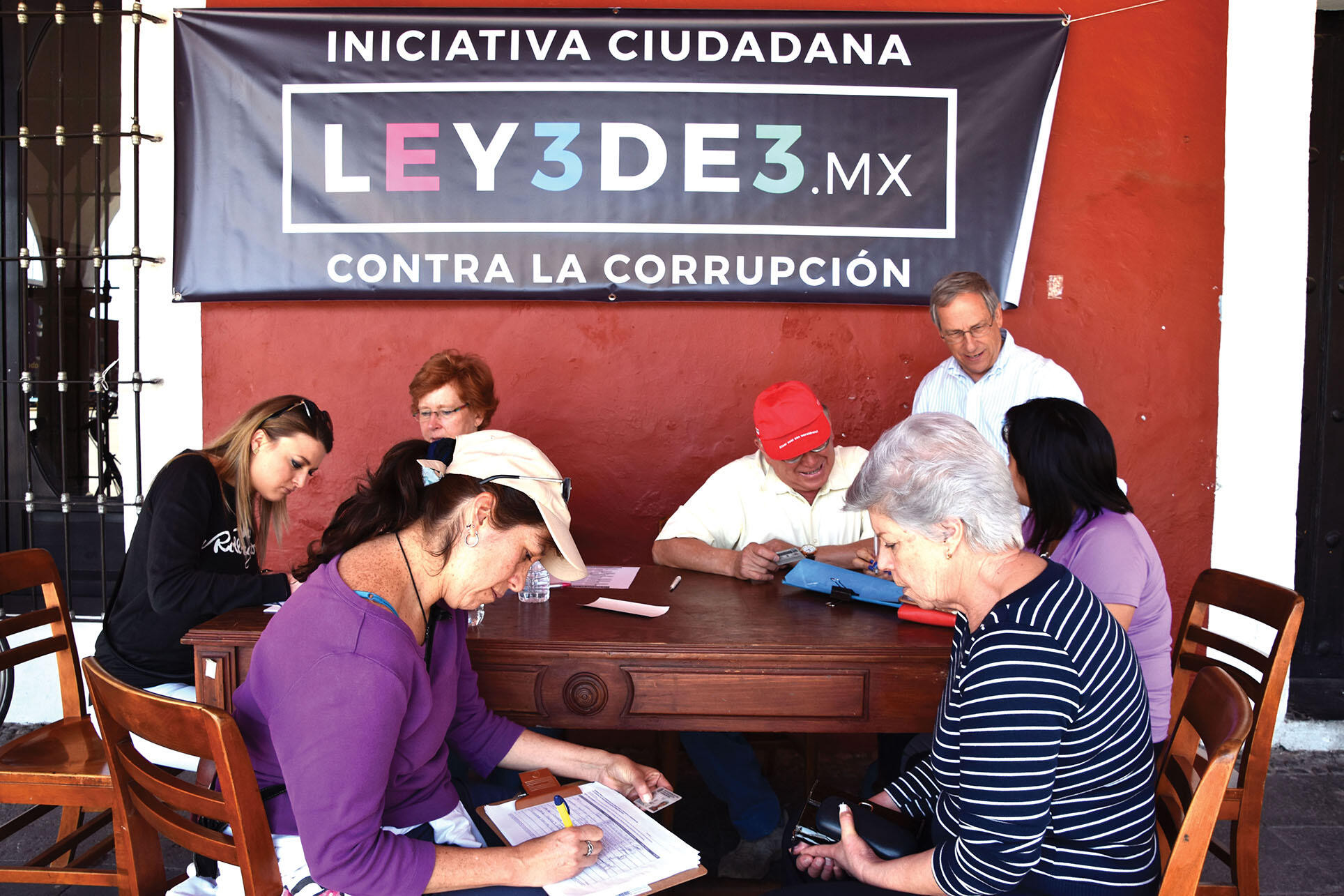 Mexicans line up at a table to sign a petition supporting the Ley 3de3 anti-corruption measure in Cholula.