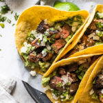 Carne Asada Tacos ready to serve with a variety of toppings.
