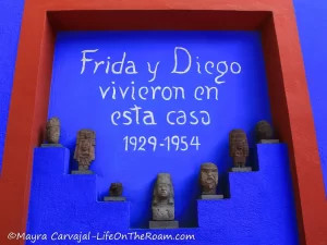 A blue wall with pre-Hispanic figurines and the text