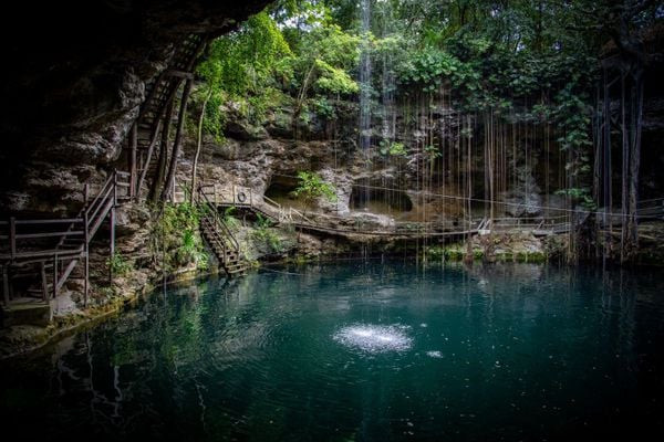 Tourists enjoying a swim in the crystal-clear waters of a cenote.