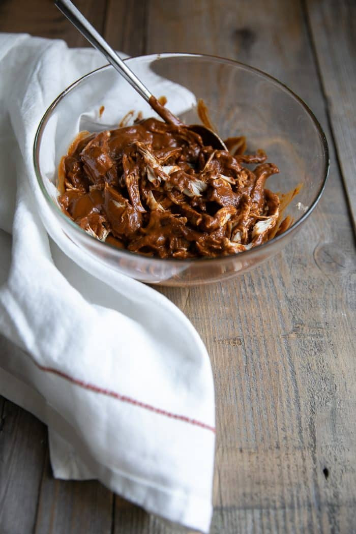 A bowl of homemade mole sauce with some shredded chicken and rice.