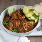 Chicken Mole served with a side of rice and garnished with sesame seeds